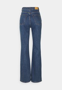 Vidbenade jeans i mörkblått. Klassisk femficksdesign med två bakfickor. Har en läderlogotyp vid midjan.