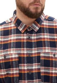 Flanellhemd mit marineblauem Grund und kariertem Muster in Orange, Rot und Weiß. Knopfleiste mit zwei Brusttaschen und klassischem Kragen.