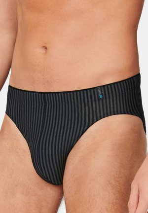 Mannelijke torso met zwarte en grijze gestreepte slip met een klein blauw label op de tailleband, tegen een effen achtergrond.