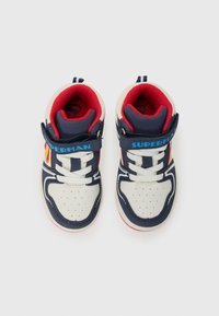 Baskets de sport pour tout-petits avec des couleurs bleu marine, rouge et blanc, affichant un logo "Superman" et une bande Velcro pour un enfilage facile.