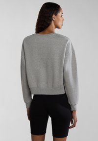 Grijze cropped sweatshirt met geribbelde onderrand en manchetten, met een drop shoulder ontwerp en een zachte textuur, gecombineerd met zwarte strakke shorts.