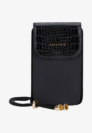 Sac bandoulière noir avec rabat texturé crocodile, lettrage doré "EXPATRIE" et cordon réglable noir avec embouts métalliques dorés.