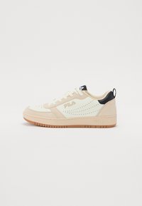 Bež ja kreem sneaker perforatsioonidega, lame paelad, must kannaosa ja pruun kummitald. Brändi logo küljel ja keeles.