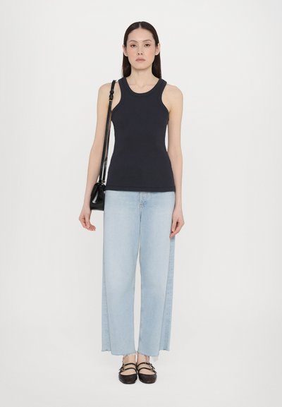 Débardeur noir à côtes sans manches, jeans bleu clair à jambe large avec ourlet effiloché, et chaussures slingback noires. Design simple avec une coupe moderne.