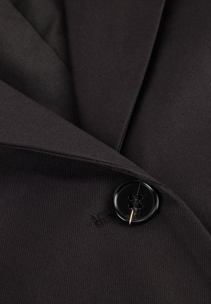 Svart blazerkåpe i stoff med en hakket slag, utstyrt med en stor svart knapp med fire hull og en subtil ribbet tekstur.