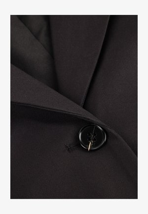 Schwarzer Stoffblazer mit einem fallenden Revers, der eine große schwarze vierlochige Knopfleiste und eine dezente gerippte Struktur aufweist.