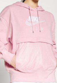 Rosa Nike-hoodie med lös passform, som har en meshnäst, huva med dragsnören och broderad logga på framsidan.