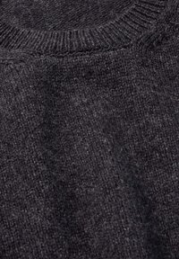Maglione a maglia testurizzata di colore grigio scuro, con scollatura rotonda e polsini a coste. Il materiale sembra morbido e leggermente peloso. Nessun motivo visibile.