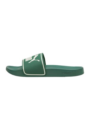 Sandale slide Puma verte avec logo blanc sur une large bride et une semelle texturée, vue de côté sur fond blanc.