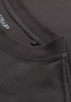 Svart sweatshirt med rund halsringning och flatlock-sömmar. Mjuk yta med synliga sömmar och en liten logotypetikett nära kragen.