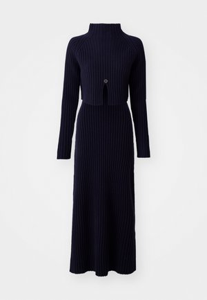 Vestido de punto acanalado en azul marino con cuello alto, mangas largas y un torso recortado que presenta un corte central y un detalle de botón.