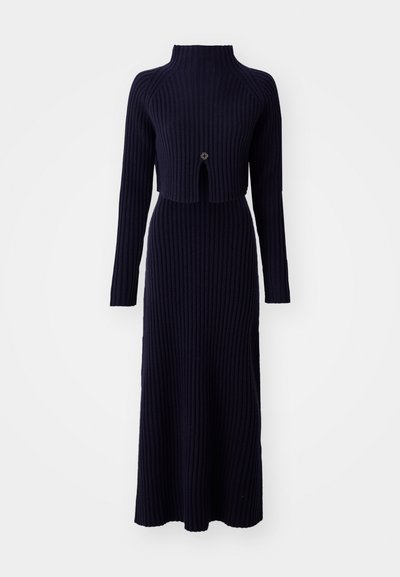 Marineblauw ribgebreid jurk met een hoge kraag, lange mouwen en een kort lijfje met een centrale uitsnede en knoopdetail.