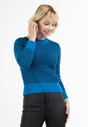 Blå strikket sweater med struktureret mønster, ribbede manchetter og kant, rund halsudskæring og tætsiddende design, parret med sorte bukser.