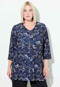 Bloemrijke tuniektop met een marineblauwe achtergrond en grote blauwe en grijze rozen, gemaakt van zachte stof, met een V-hals en 3/4 mouwen.