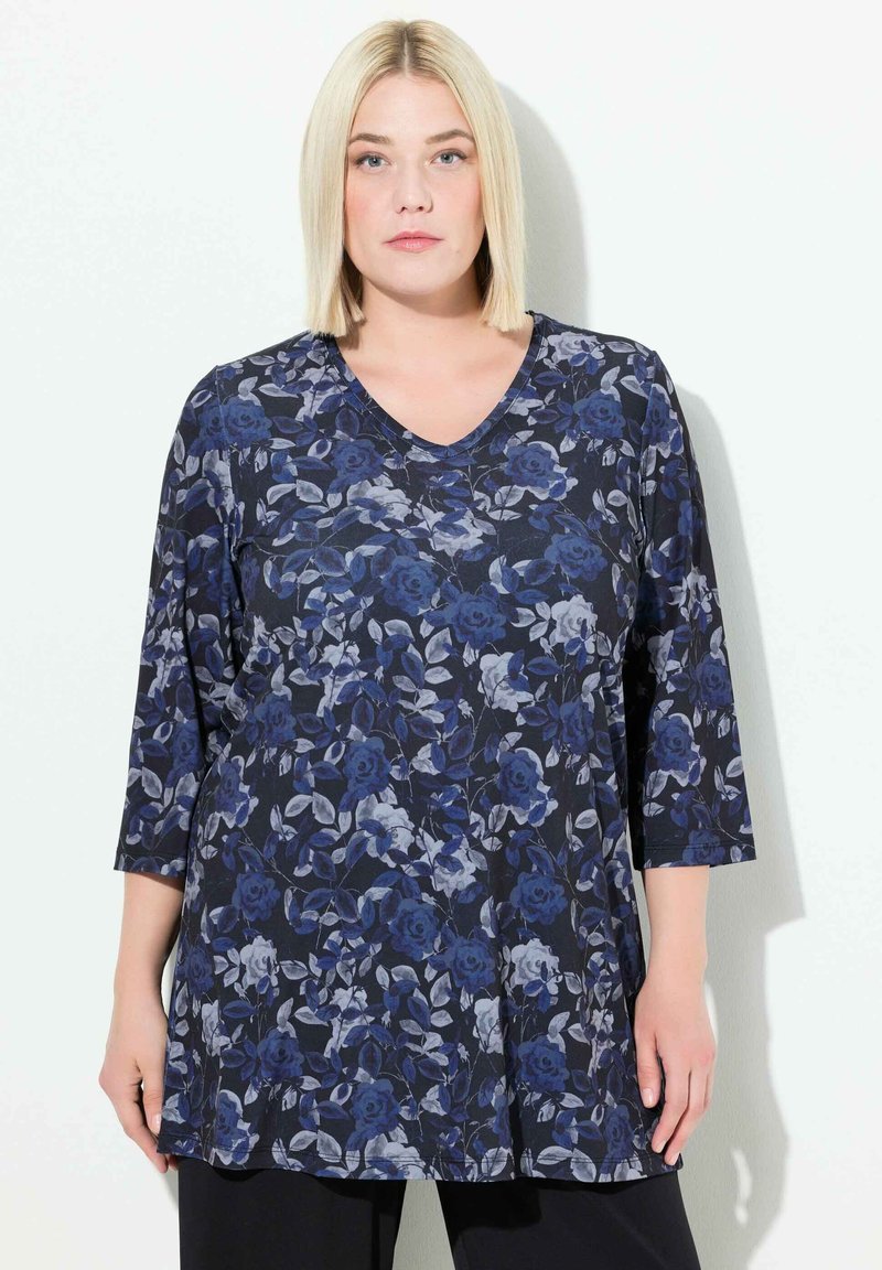 Bloemrijke tuniektop met een marineblauwe achtergrond en grote blauwe en grijze rozen, gemaakt van zachte stof, met een V-hals en 3/4 mouwen.