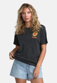 Sort bomulds T-shirt med rund halsudskæring og korte ærmer, der har et farverigt grafisk logo på fronten. Sammen med lyse denimshorts.