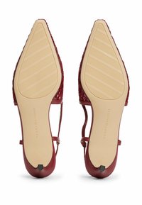 Escarpins rouges à talons avec une texture tissée, bout pointu et semelle en caoutchouc nude avec des rainures horizontales et un logo sur le talon.