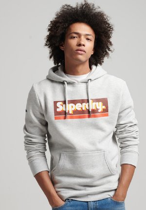 Sudadera gris con un gran logo multicolor de "Superdry" en el pecho, con un bolsillo tipo canguro y cuerdas ajustables en la capucha.