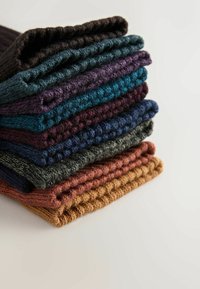 Bunke af strikkede tørklæder i forskellige farver: brun, teal, mørk lilla, blå, grøn, rust og orange. Taktile mønstre med ribbede kanter.