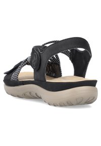 Zwarte sandalen met gestructureerde banden, een gevoerde binnenzool en een rubberen buitenzool met een golfpatroon. Verstelbare sluiting voor een veilige pasvorm.