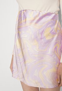 Saia curta em cetim com um padrão de mármore em tons de lavanda, amarelo e creme, com um cós elástico.