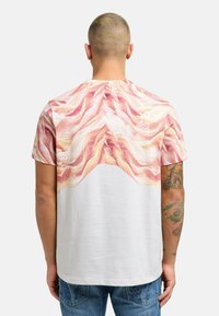 T-skjorte med korte ermer som har en rosa baconmønster på ryggen og hvit front, laget av mykt stoff med en avslappet passform og rund hals.