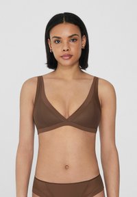 Soutien de color marrón sin cables con un diseño en V, fabricado en una tela suave. Presenta tirantes anchos y un frente cruzado para mayor comodidad y soporte.