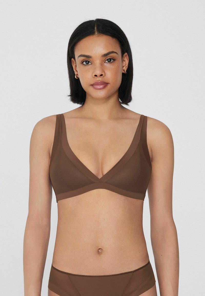 Soutien de color marrón sin cables con un diseño en V, fabricado en una tela suave. Presenta tirantes anchos y un frente cruzado para mayor comodidad y soporte.
