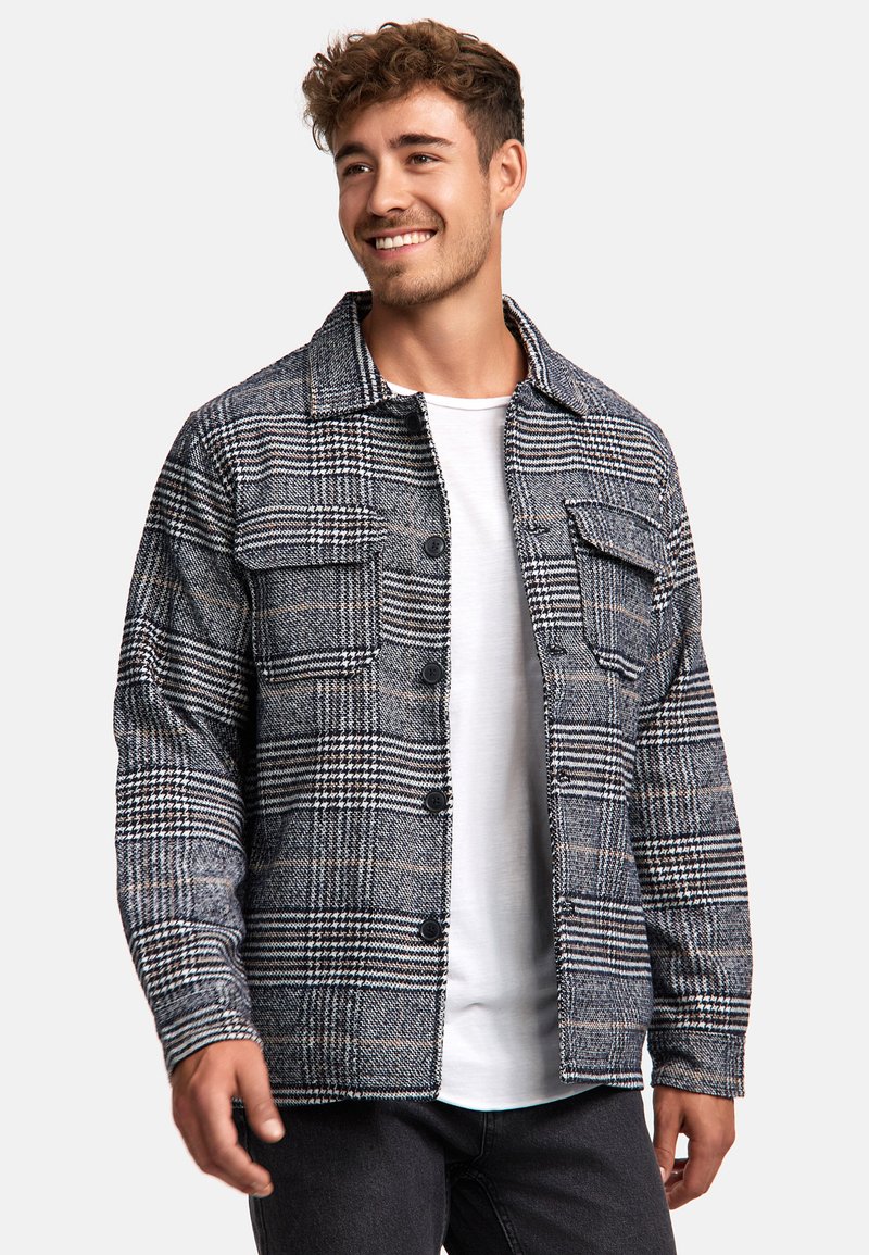 Plaid jacket in black and white with beige accents; features button closure and two front pockets; fabric appears textured and warm.