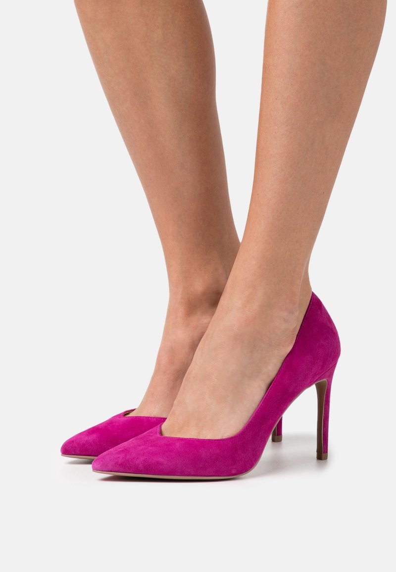 Escarpins en daim fuchsia à talons hauts avec bouts pointus, une texture lisse et un design à talon aiguille, présentant une silhouette classique.