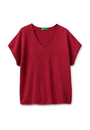 Rode gebreide top met korte mouwen, V-hals en een getextureerd horizontaal ribbelpatroon, met een groen label bij de halslijn.