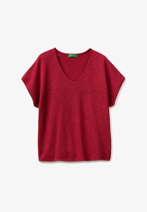 Czerwony krótki sweterek z dzianiny z dekoltem w serek i teksturowanym poziomym prążkowaniem, z zieloną metką przy dekolcie.