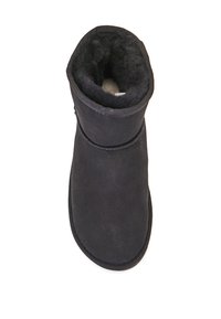 Czarne zamszowe botki z miękką podszewką, zaokrąglonym noskiem i złożonym mankietem. Podeszwa jest płaska z subtelną teksturą dla lepszej przyczepności.