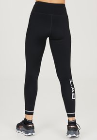Leggings de sport noirs avec taille haute, poches latérales en mesh et accents de logo blancs. Texture lisse et design ajusté.