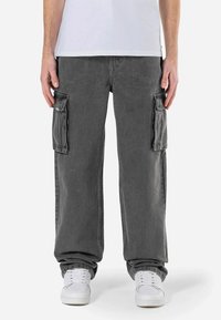 Grijze cargobroek van denim, met twee zijzakken, een losse pasvorm en opgerolde hems. Draagt met witte sneakers en een eenvoudig wit shirt.