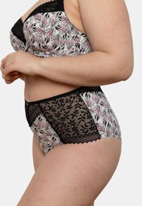 Ensemble brassière et culotte taille haute avec un motif floral en blanc, noir et rose. Finition en dentelle noire et accents sur la culotte.