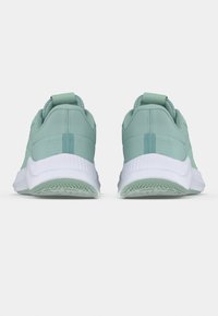 Ζευγάρι ανοιχτό πράσινα αθλητικά παπούτσια με λευκές σόλες, εμφανιζόμενα από πίσω, όρθια σε λευκή επιφάνεια με φωτεινό φόντο.