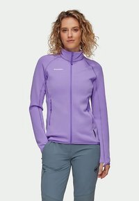 Jachetă din fleece violet, cu guler înalt și fermoar complet, având buzunare laterale și cusături în contrast. Textură netedă, design ajustat.