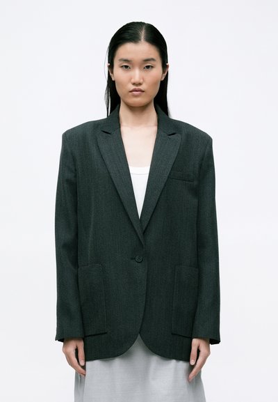Grauer Wollblazer mit lockerer Passform, Ein-Knopf-Verschluss, Reverskragen und zwei Fronttaschen. Glatte Textur und minimalistisches Design.