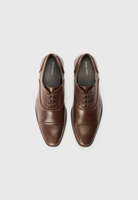 Chaussures habillées en cuir marron avec une finition lisse, dotées d'un bout pointu, de lacets et d'une accent texturé sur les côtés.