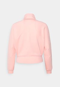 Sudadera corta de color rosa claro con un cuello alto, mangas largas y una textura suave. Presenta costuras de estilo raglán y puños acanalados.