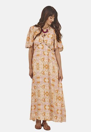 Vestido maxi con estampado floral en tonos naranja, amarillo y púrpura. Mangas cortas abullonadas, escote en V y falda fluida. Combinado con sandalias planas.