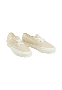 Sneakers in tela di un beige chiaro con lacci bianchi, suole in gomma e design a punta rotonda. Estetica minimalista senza loghi o motivi visibili.