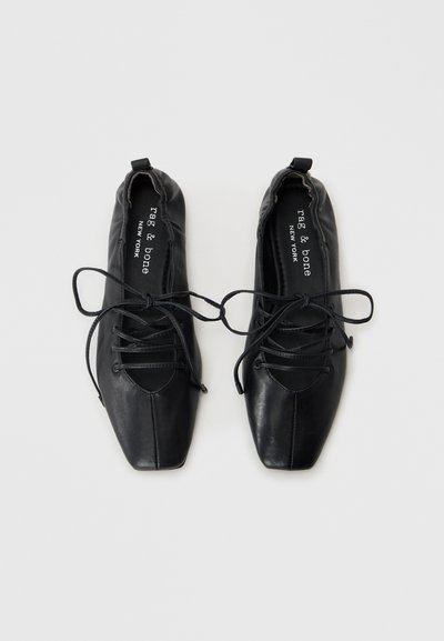 Chaussures en cuir noir avec un design à bout pointu, dotées de lacets et d'une texture douce et lisse. Comprend le nom de la marque sur la semelle intérieure.