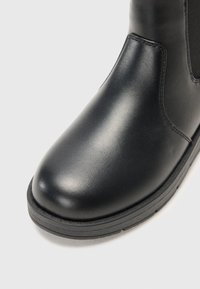 Sorte lærankelstøvler med rund tå og elastiske sideskafter. Tykk gummisåle med teksturert grep. Glatt finish og robust design.
