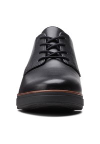 Chaussure de ville pour homme en cuir noir avec laçage fermé, bout rond, garniture marron au-dessus de la semelle en caoutchouc noire, vue de face sur fond blanc.