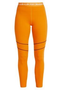 Pomarańczowe legginsy sportowe o dopasowanym kroju, z czarnymi akcentującymi paskami i białym paskiem w talii oznaczonym "CALVIN KLEIN PERFORMANCE."