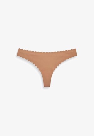 Tanga nude con bordes ondulados. Fabricada con un material suave y liso, presenta un diseño minimalista y tirantes delgados.