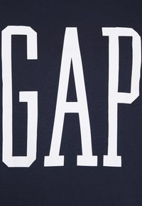 T-shirt in cotone blu navy con grandi lettere bianche in maiuscolo che scrivono "GAP" sulla parte anteriore. Texture morbida, design con collo a giro.