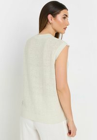 Top senza maniche in maglia beige chiaro con scollo rotondo a costine e motivo testurizzato, caratterizzato da una vestibilità comoda e dettagli di cucitura discreti.